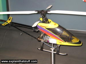 A yellow radio-controlled helicopter mounted as a science museum exhibit.